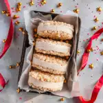 Rice Crispy Ice Cream Sandwiches - Easy, Cool & Viral 9 Rice Krispie Treat Ice Cream Sandwiches stacked in a tray with vanilla ice cream