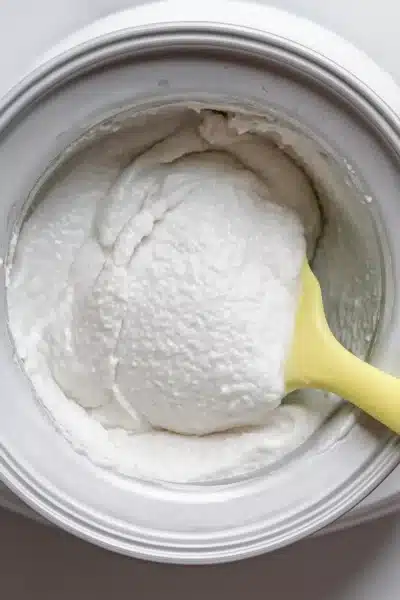 Scooping creamy coconut sorbet from machine – coconut sorbet in shell