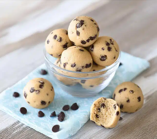 Cookie dough protein bites stacked in a glass bowl with chocolate chips