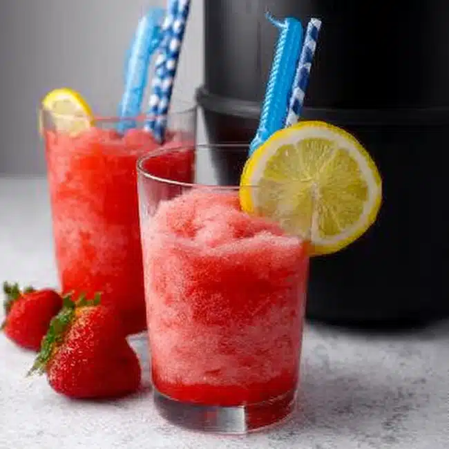 Ninja Creami slushie recipe with strawberries and lemon garnish in a glass
