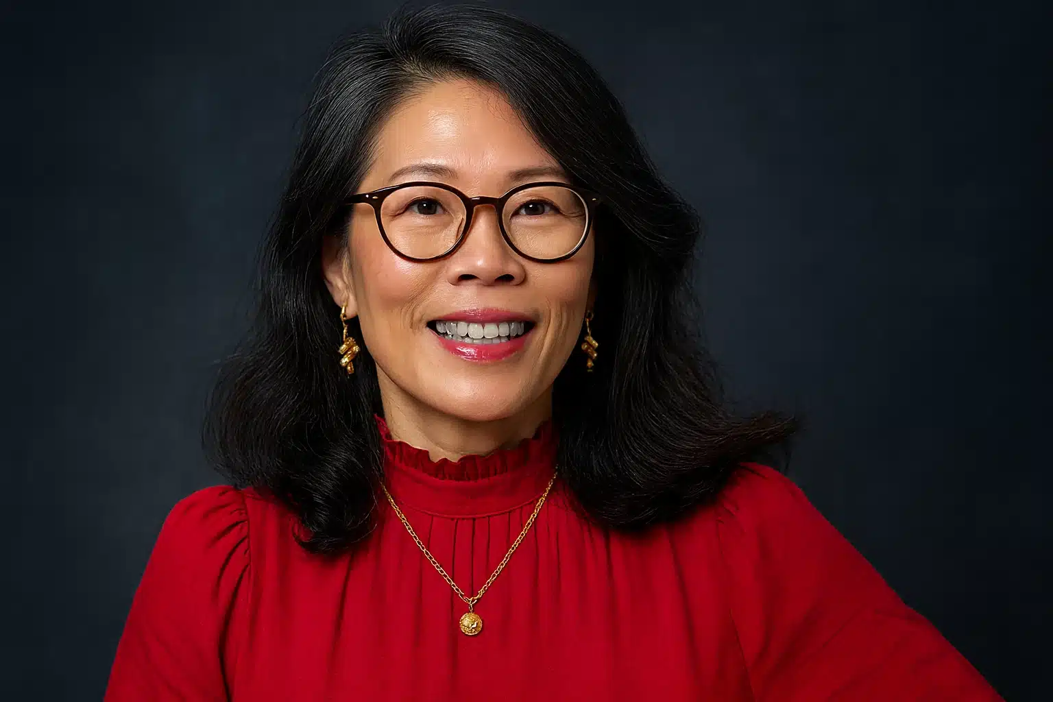 Confident smiling woman in red blouse and glasses, representing expert insights related to Dr. Wendy Suzuki pink salt benefits.