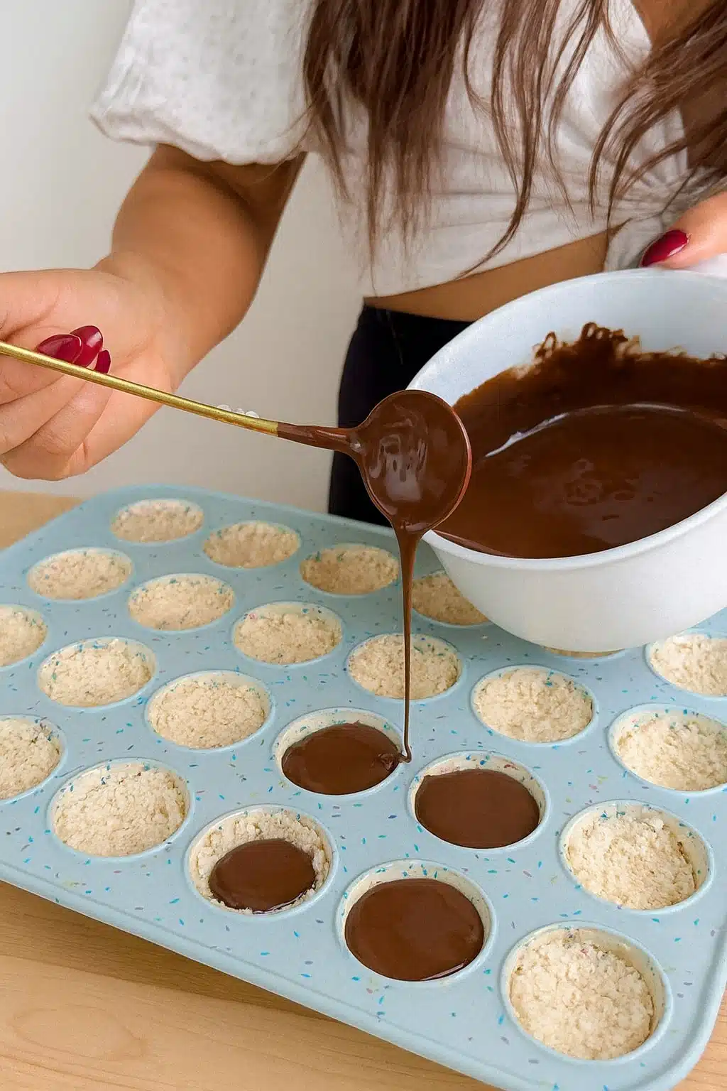 pouring melted chocolate over coconut base for healthy almond joys
